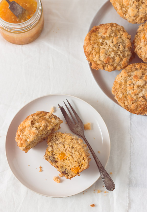 Overhead views of delicious mango muffins cut in half on a white plate, exposing the bits of mango inside the muffin.