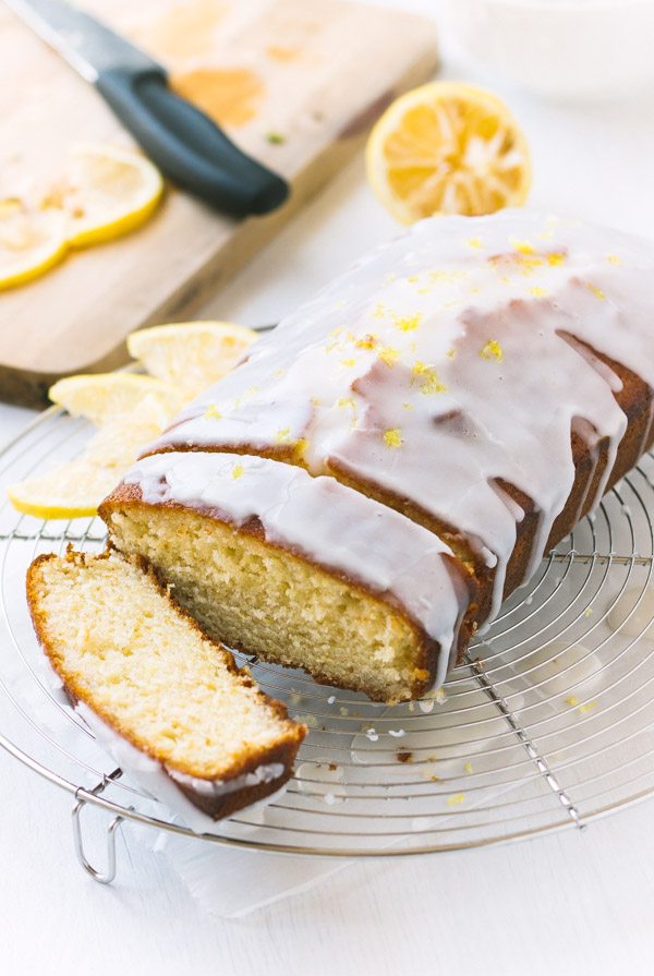 Perfect Lemon Loaf Cake with lemon slices on the side and fresh zest covering the lemon glazed top.