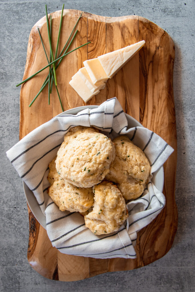 white cheddar, chives, and biscuits on an olive wood board