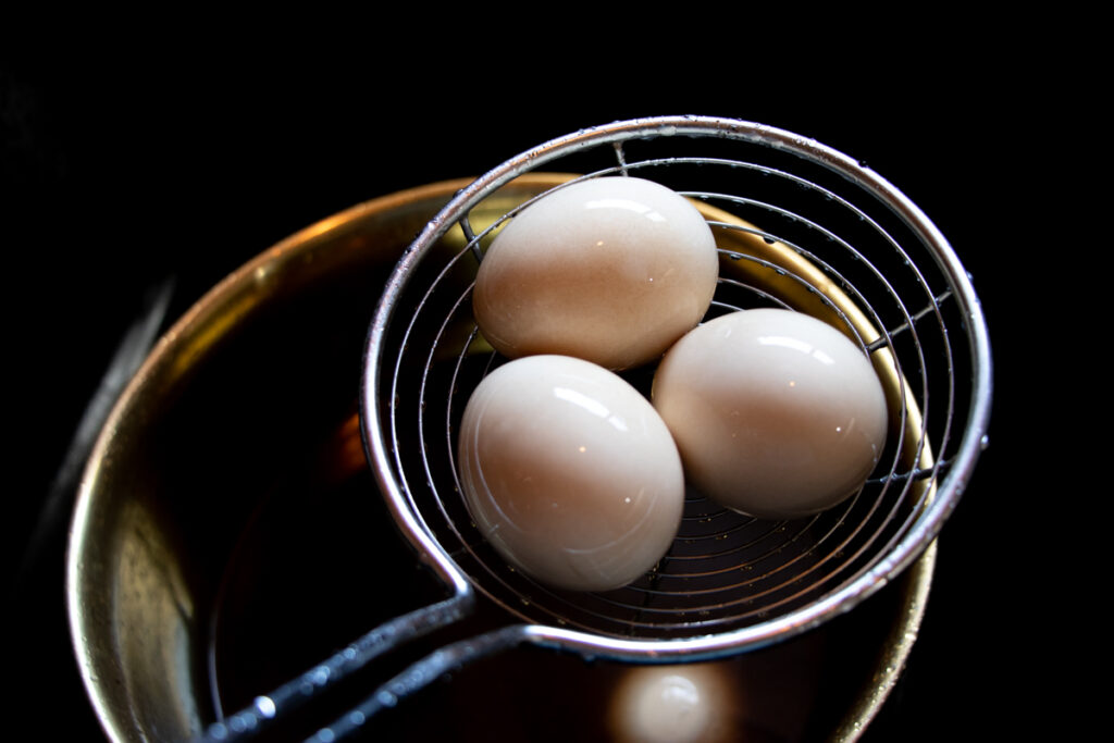 hard boiled eggs in a strainer spoon