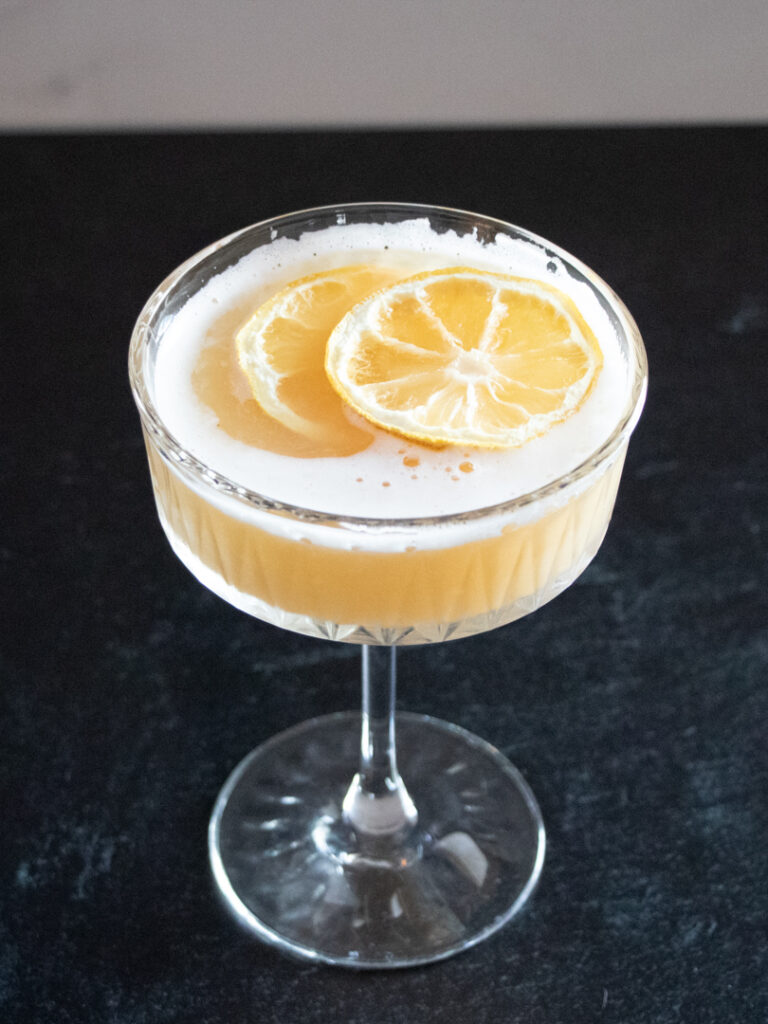 whiskey sour cocktail made with egg whites garnished with lemon slices