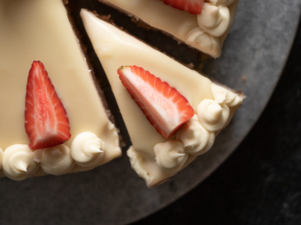 slice of strawberry cheesecake with white chocolate ganache whipped frosting