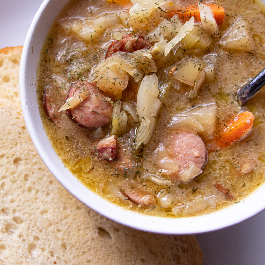 bowl of sauerkraut soup with kielbasa sausage and dill