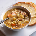 bowl of sauerkraut soup with kielbasa sausage and bread