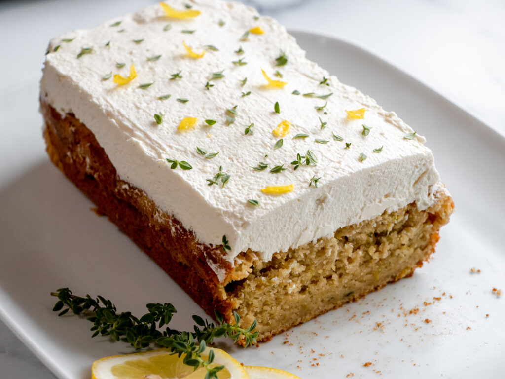 Lemon Zucchini Cake with stabilized whipped cream frosting topped with lemon zest and fresh thyme