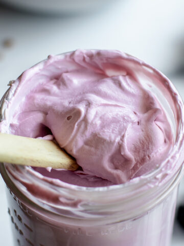 A jar of light purple whipped blackberry frosting made with mascarpone cheese and fresh blackberries.