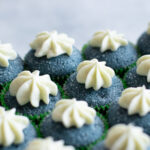 Artificial dye-free blue cream cupcakes with dollops of cream cheese frosting.