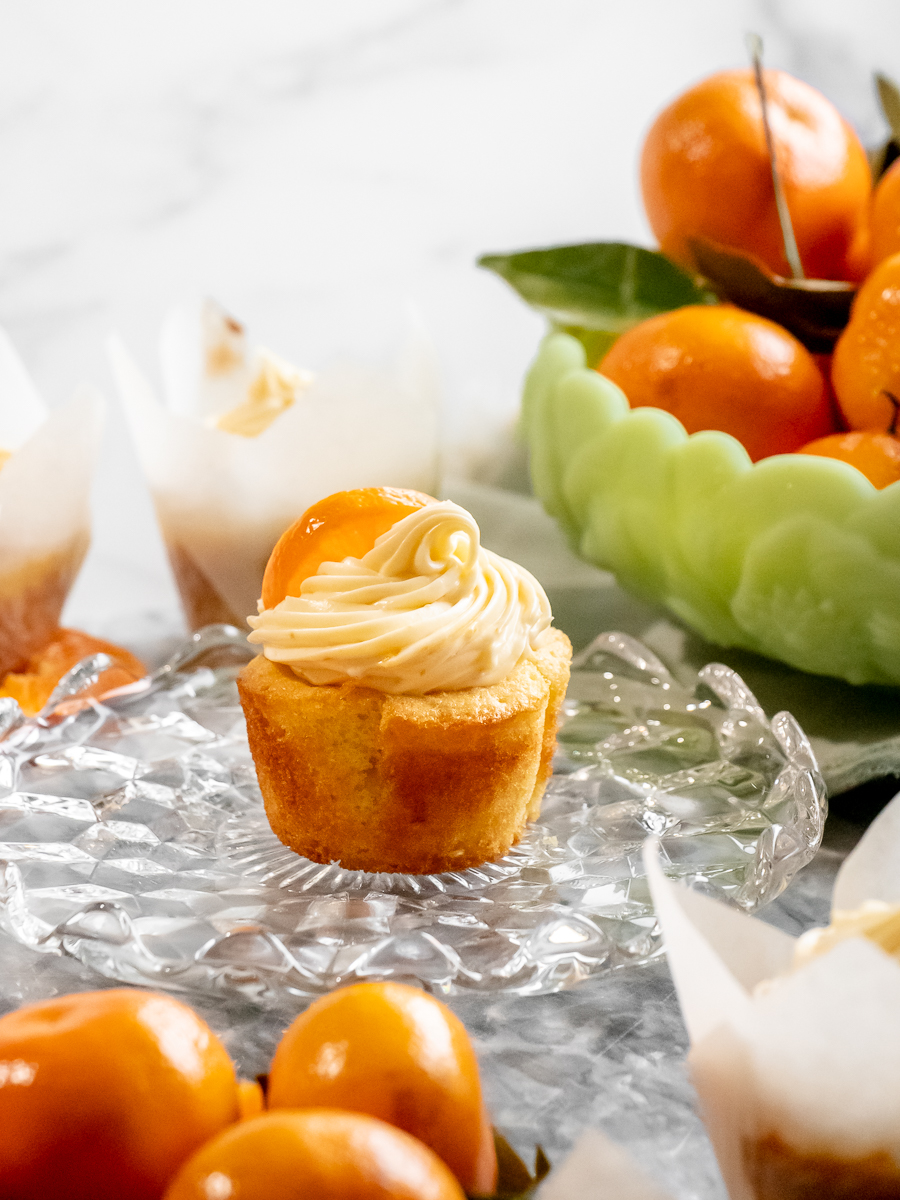 Sun shining down on a bright orange citrus bowl and a frosted orange cupcake.