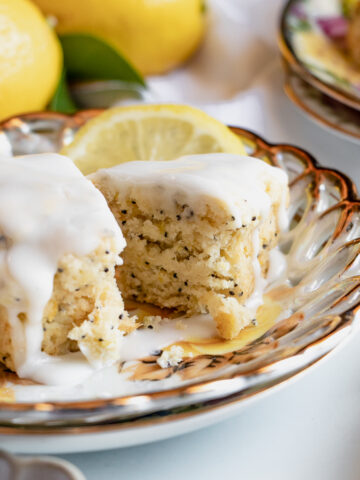 Moist lemon poppy seed scone broken in half to show its texture, topped with icing and styled with fresh citrus.