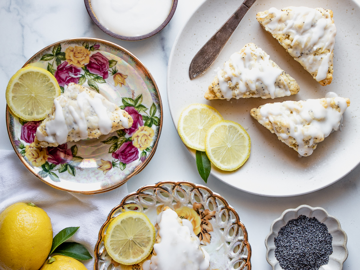 Assorted lemon poppy seed scones on decorative plates, styled for a bright and cheerful springtime setting.